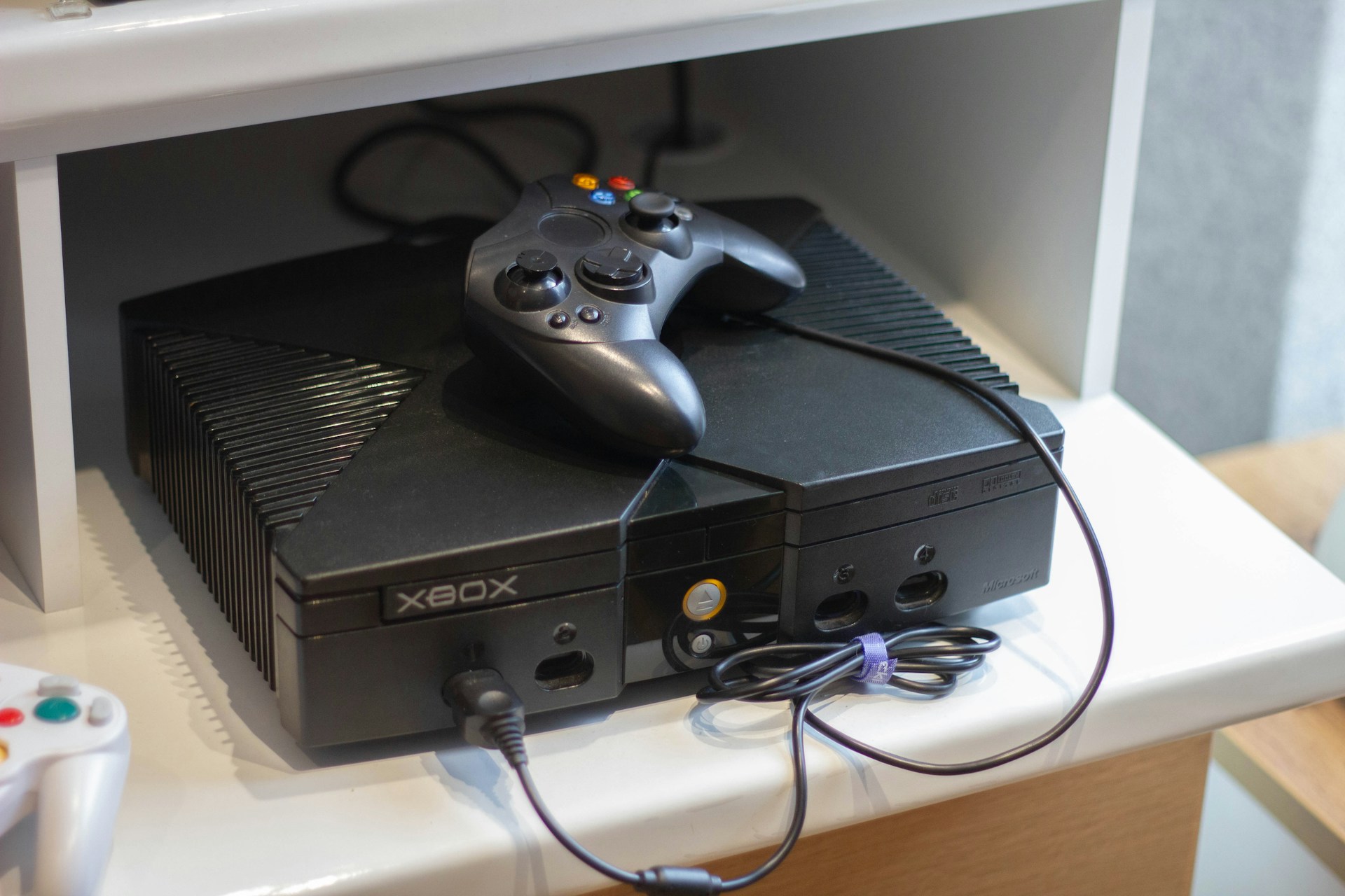 Original Microsoft Xbox console with controller on a media shelf