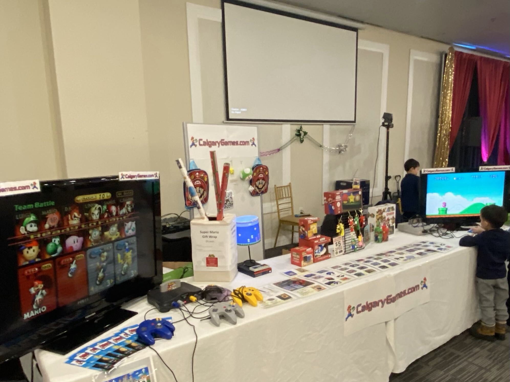 Calgary Games at the Calgary Bitcoin Sat Market — wide view of the retro gaming booth with Smash Bros on the demo TV